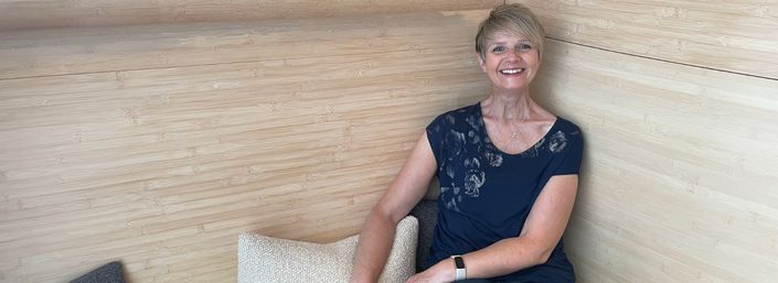 Photo of centre visitor, Mandy, smiling, as she sits at Maggie's Barts