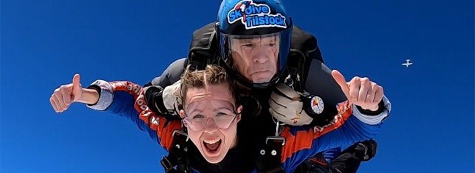 Woman and man skydiving with clear blue skies in background