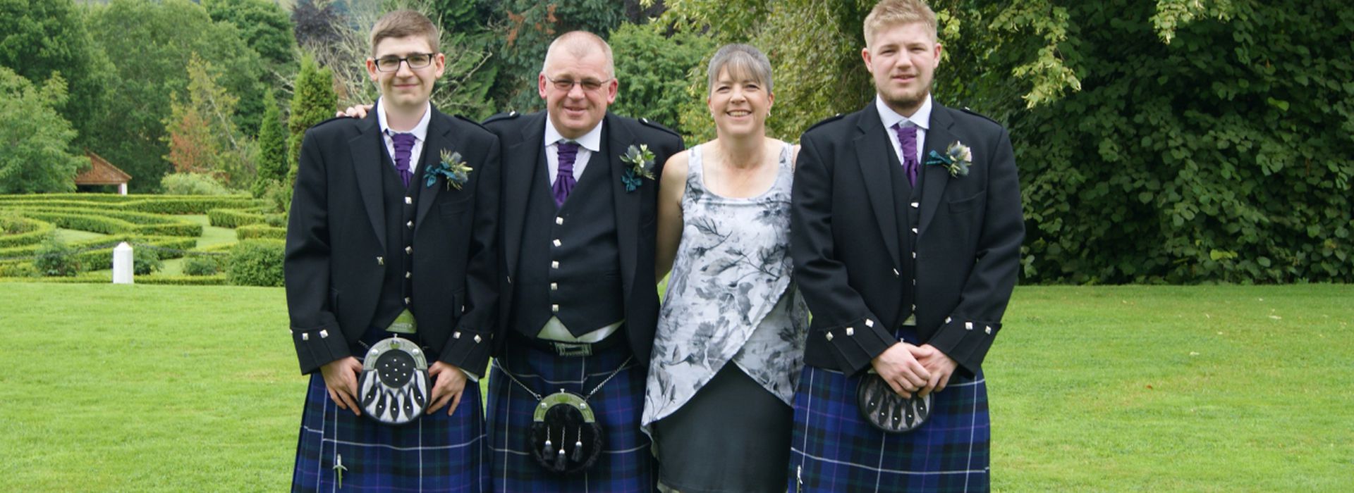 Davy, wearing kilt, with partner and sons standing for family photo