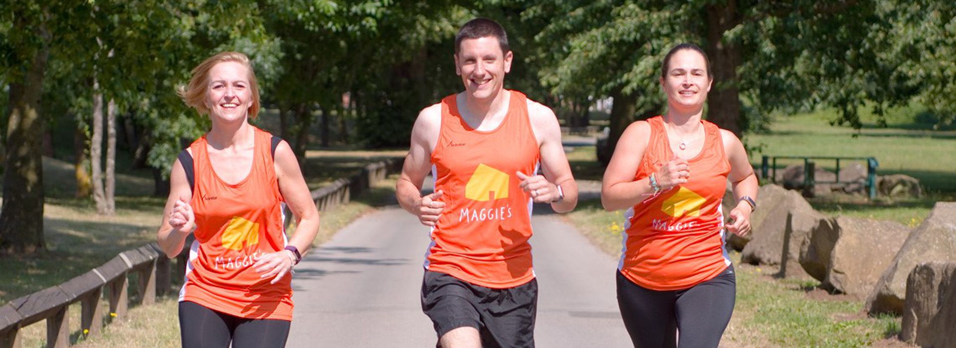 Three runners wearing Maggie's orange running vest