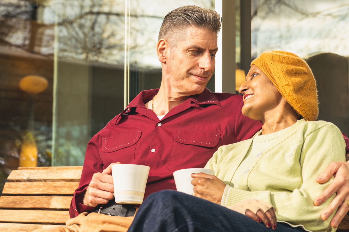 Seema and Lee sitting on a bench and looking lovingly at each other