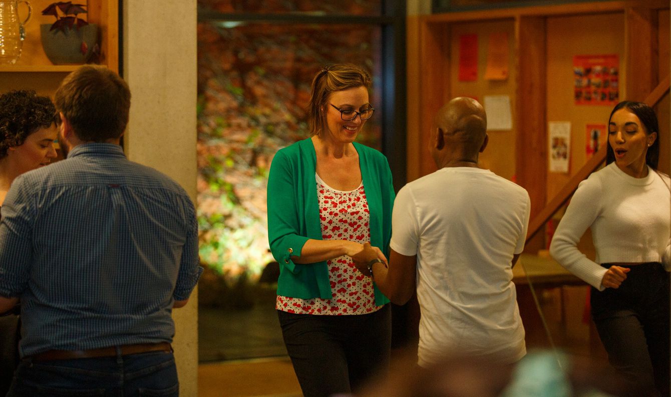 Two couples practising salsa steps with teacher Michelle watching and dancing with them