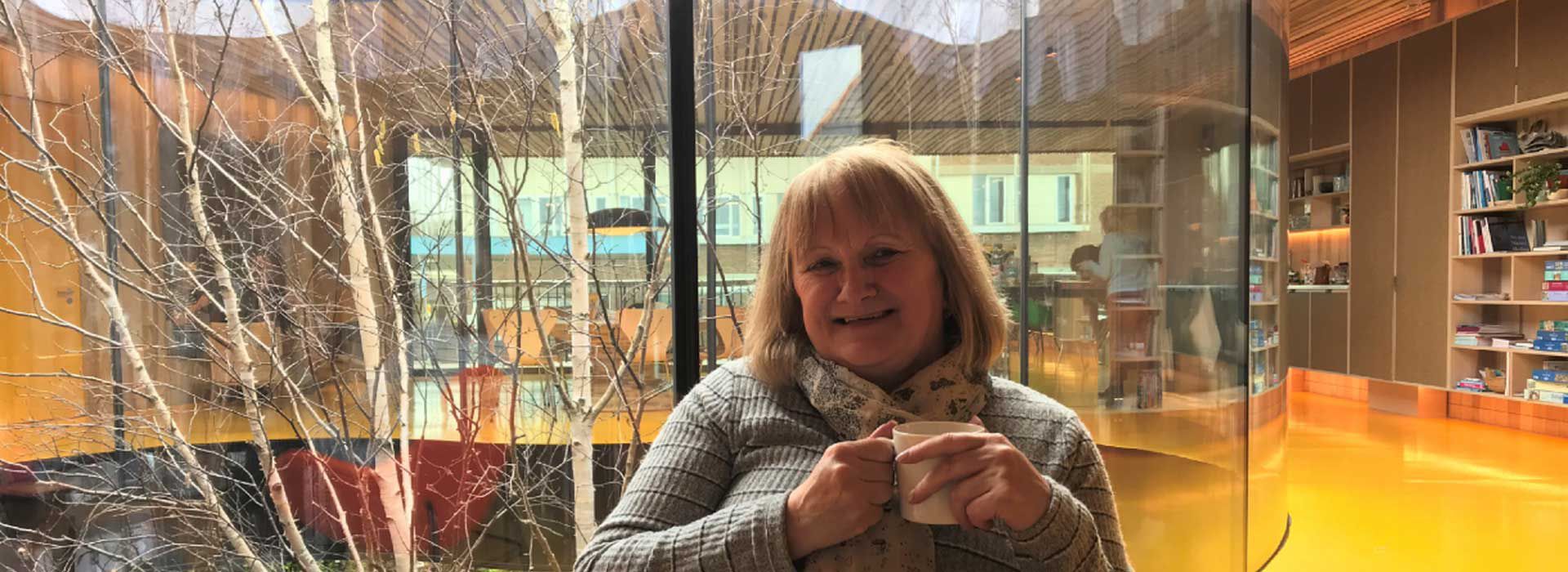 Carole smiling holding a mug in our Oldham centre