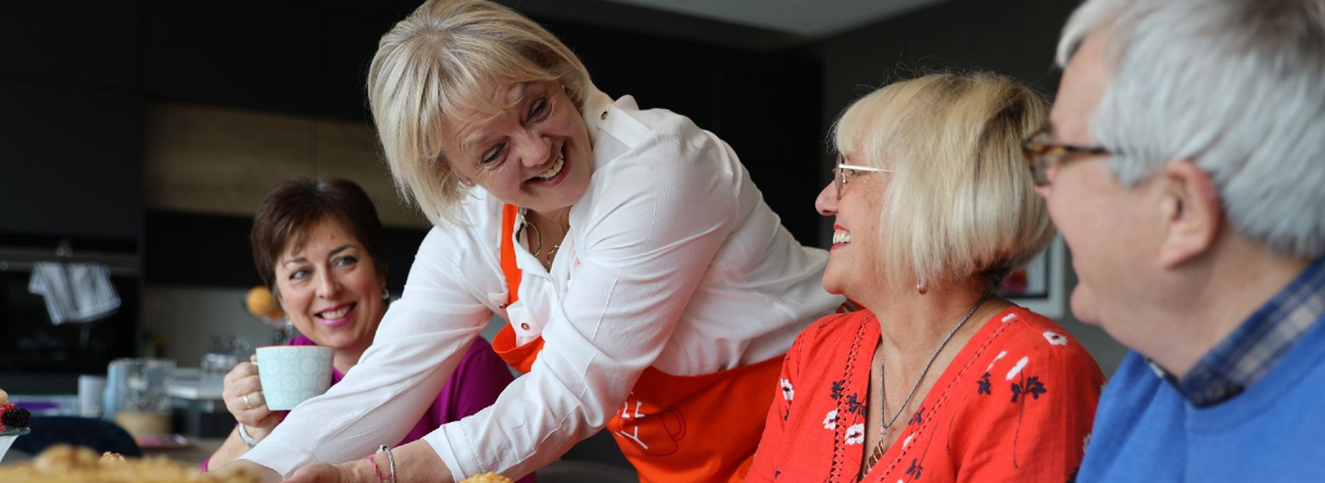 Christine, smiling and serving cake to friends at her Kitchen Table Day