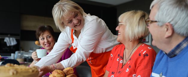 Christine, smiling and serving cake to friends at her Kitchen Table Day
