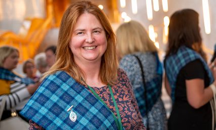 Eilidh Wilson smiles wearing tartan sash and brooch as award Queen's Nurse title