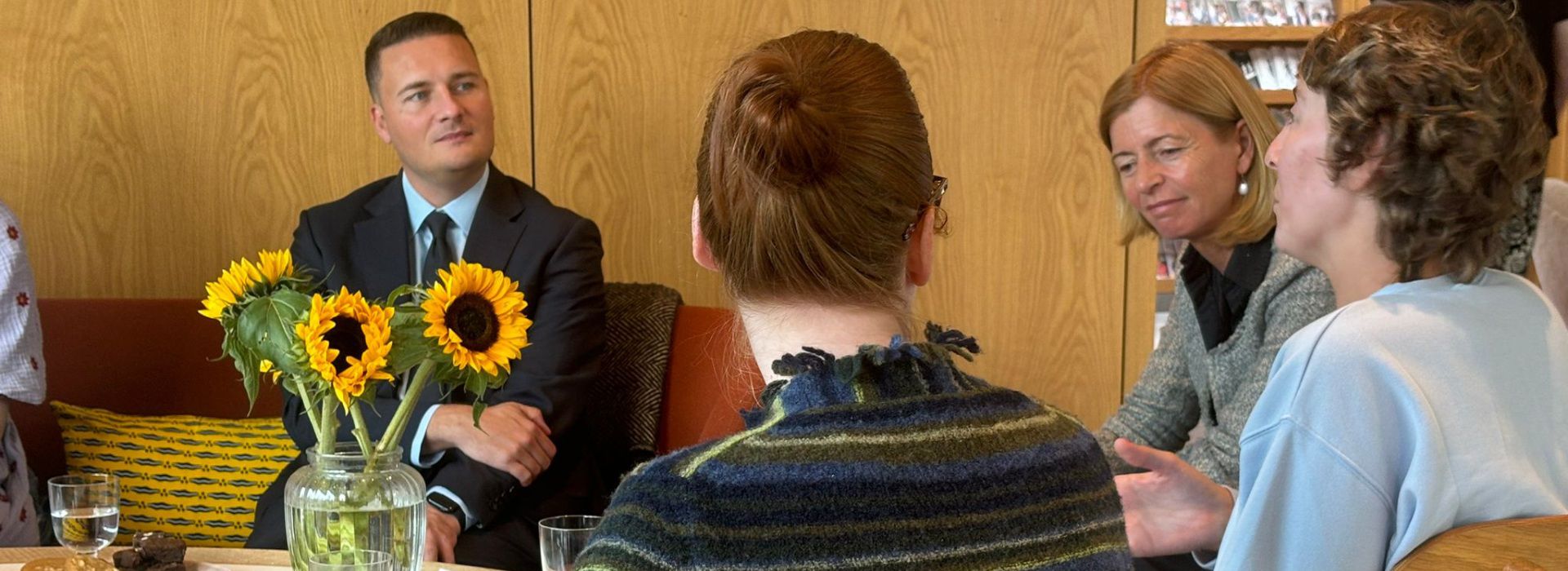 Wes Streeting MP sits with Dame Laura Lee and centre visitors at Maggie's, Wirral