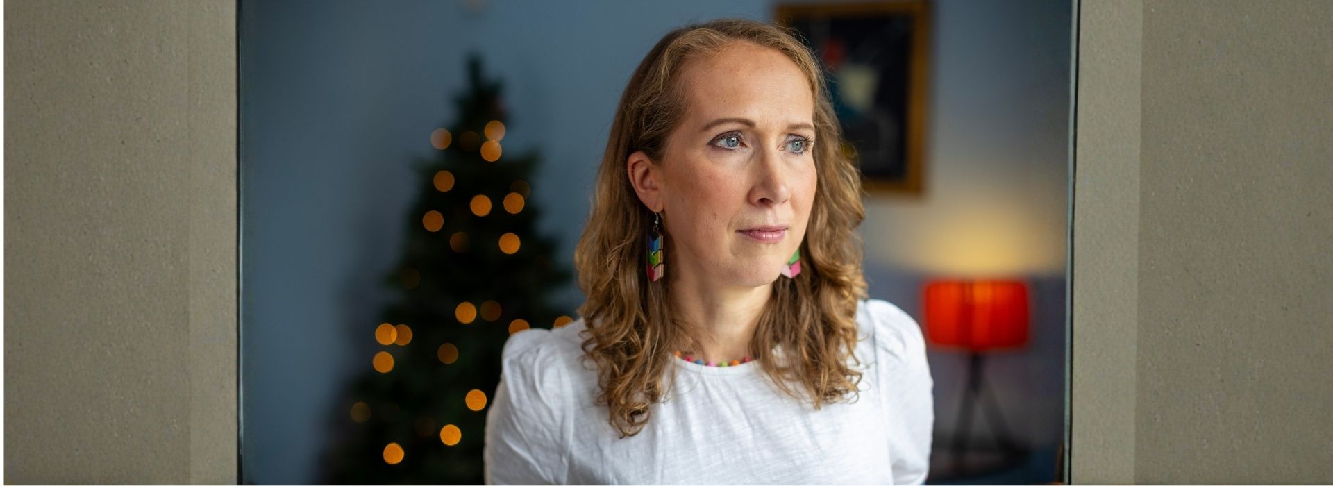 Maggie's centre visitor Cat reflects, looking into the distance, with Christmas tree in background