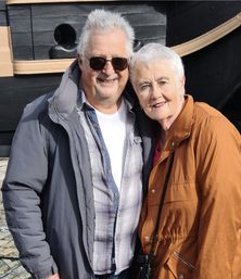 Marcus and wife Maggie standing together outside on sunny day day, smiling