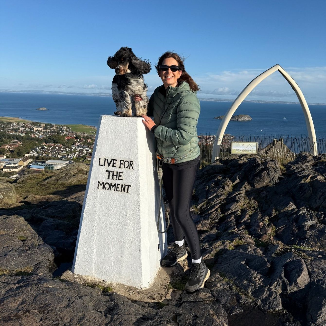 White summit post with dog on top and woman smiling