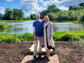 Dame Laura Lee and Darren Hawkes standing shoulder to shoulder in front of the Maggie's Forth Valley lake