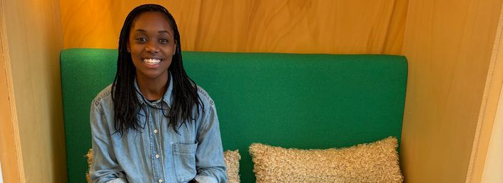Lizzi smiling and sitting on a green sofa in our Royal Marsden centre