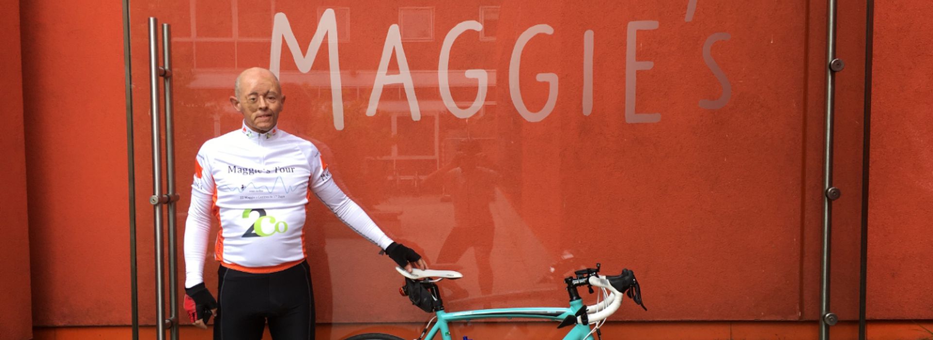 Graeme, standing in front of Maggie's, West London, wearing cycling kit and holding bike
