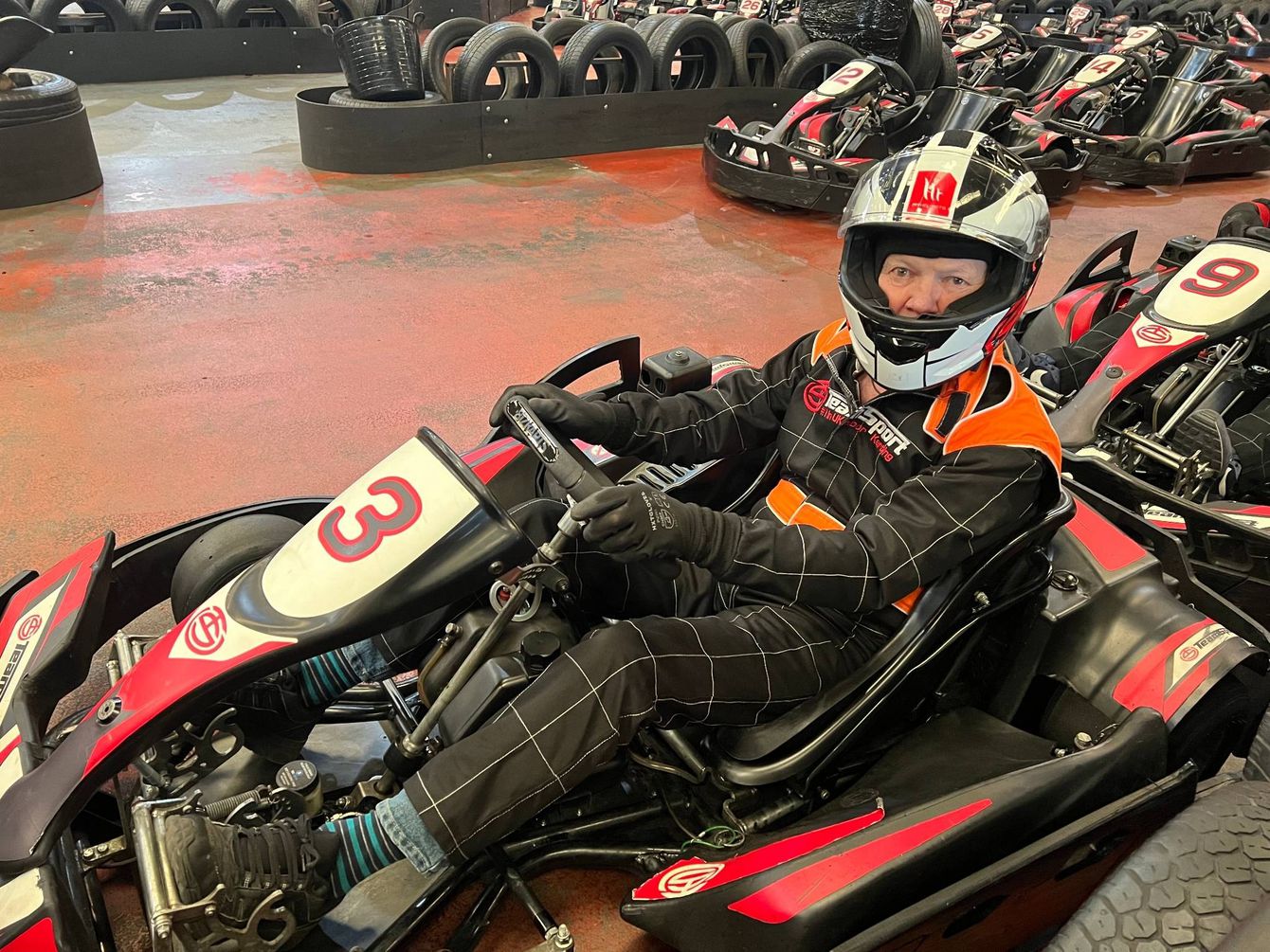 Peter, Centre Visitor, in a black go-cart wearing helmet and full racing suit.