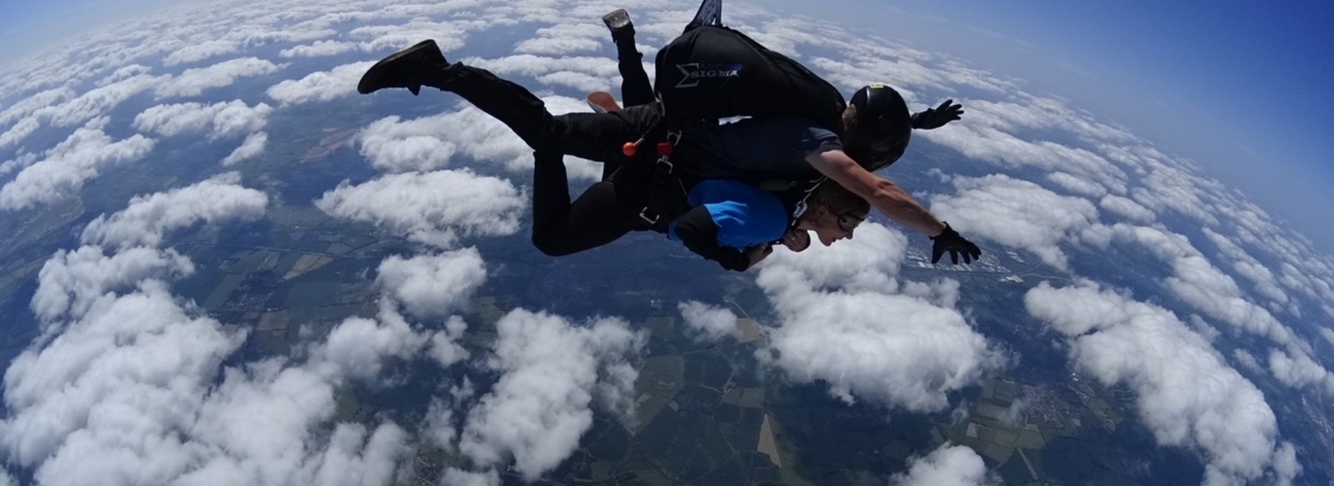 Wide-angle shot of tandem skydive above the clouds
