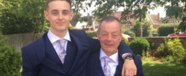 Patrick and his son wearing suits smiling and hugging