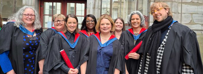Students from Abertay University in official graduation outfits smiling