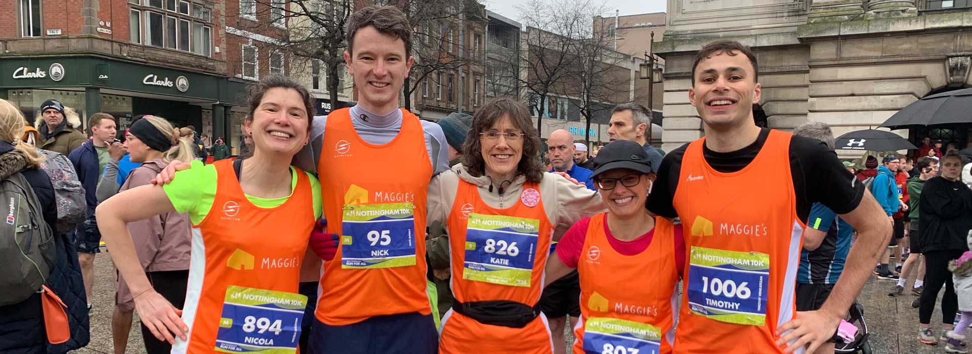 Runners smiling in Maggie's orange vests in Nottingham