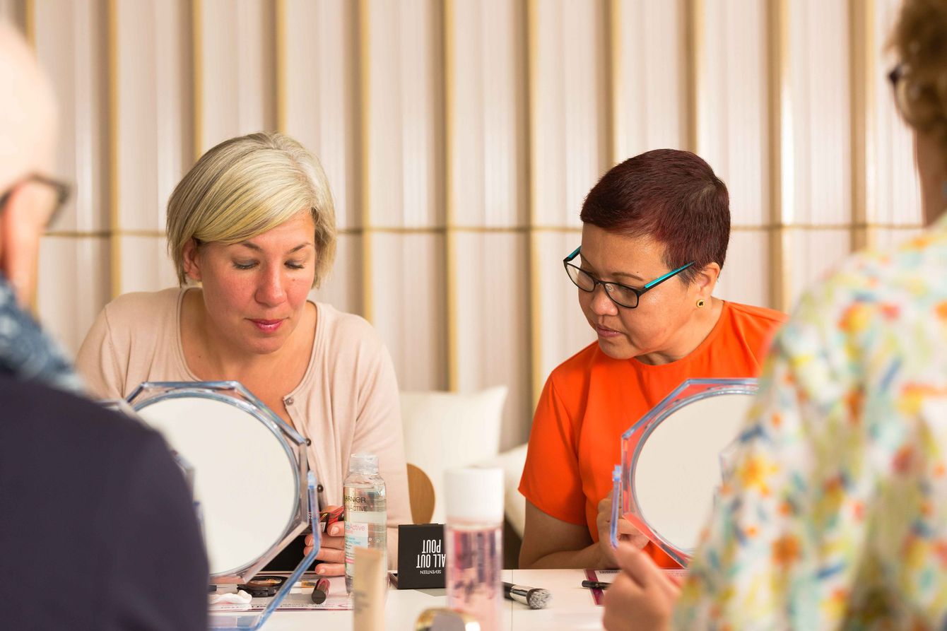 Two women swatching makeup as part of a workshop