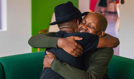 Two men hugging and smiling in warm embrace