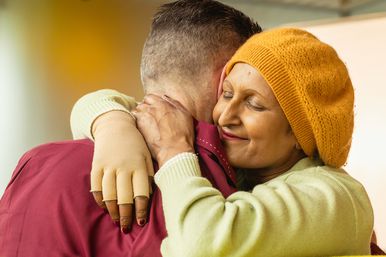 Seema is hugging her husband Lee, she is smiling